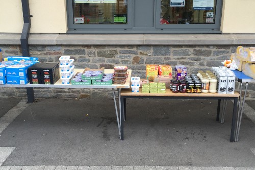 Weekly stall offering cereal, milk, pasta and other long-life grocery items as well as fresh produce set up in a primary school playground.